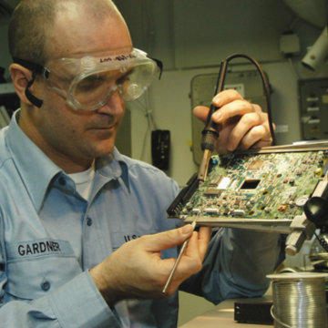 Photo of man examining a PCB